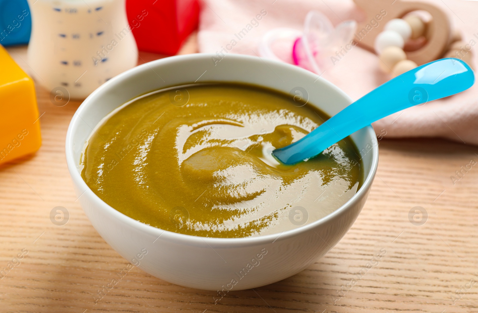 Photo of Bowl of healthy baby food on wooden table, closeup