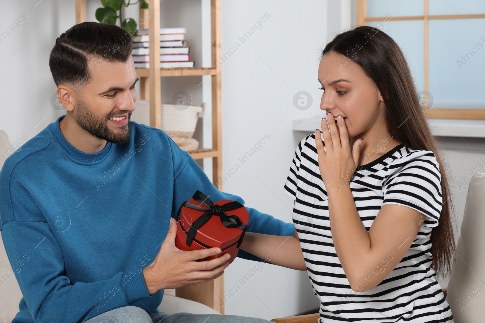 Photo of Man presenting gift to his girlfriend at home