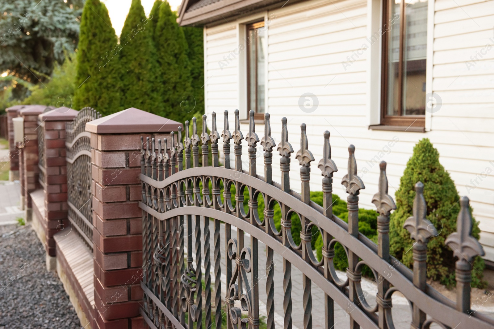 Photo of Beautiful brick fence with iron railing outdoors