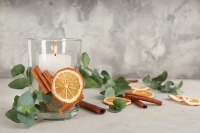 Stylish holder with burning candle and decor on light stone table. Space for text