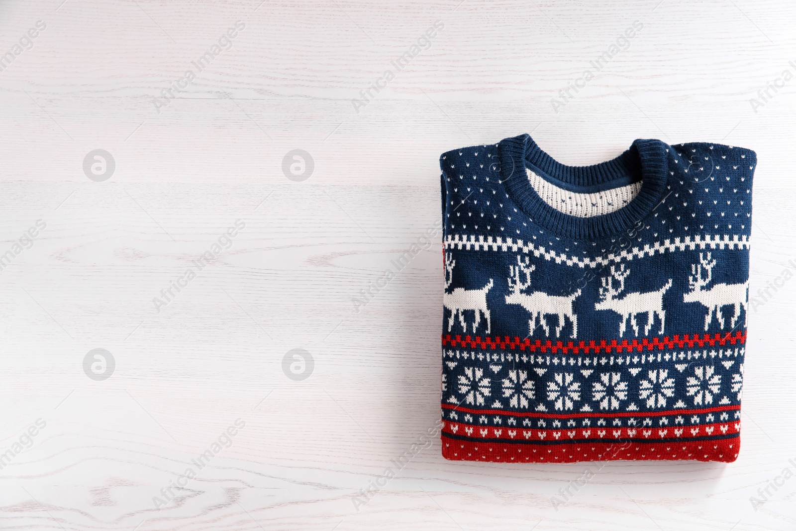 Photo of Christmas sweater with pattern and space for text on wooden background, top view