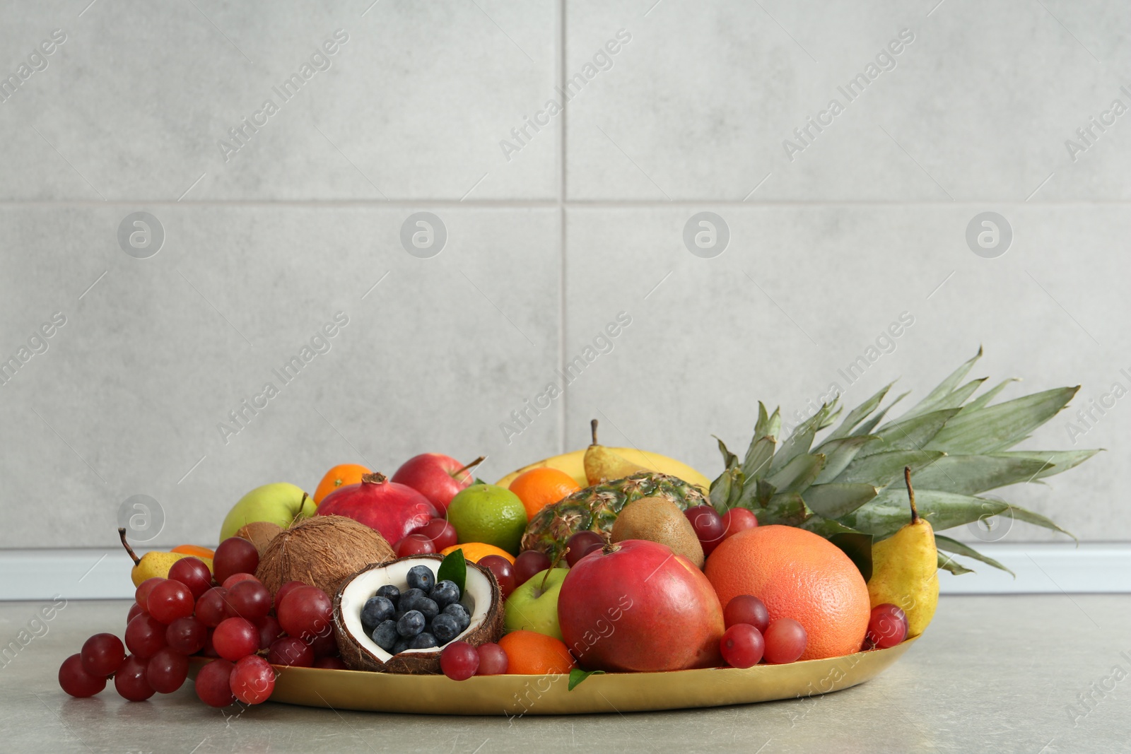 Photo of Assortment of fresh exotic fruits on grey table. Space for text