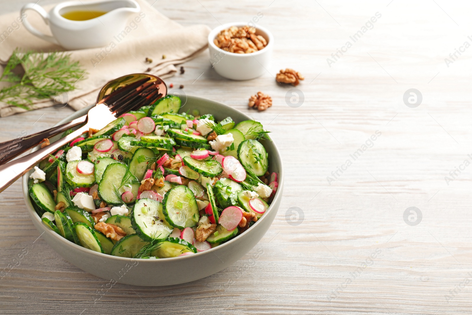 Photo of Delicious cucumber salad served on white wooden table. Space for text