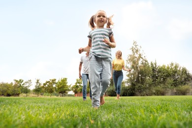 Happy family running in park on summer day, low angle view