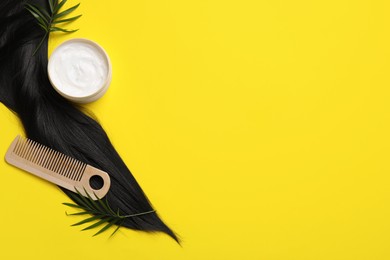 Lock of healthy black hair, cosmetic product and comb on yellow background, flat lay. Space for text