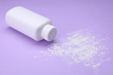 Photo of Bottle and scattered dusting powder on violet background. Baby cosmetic product