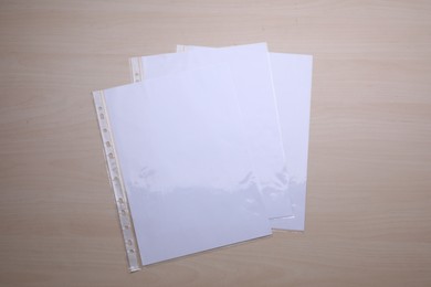 Photo of Punched pockets with paper sheets on wooden table, flat lay