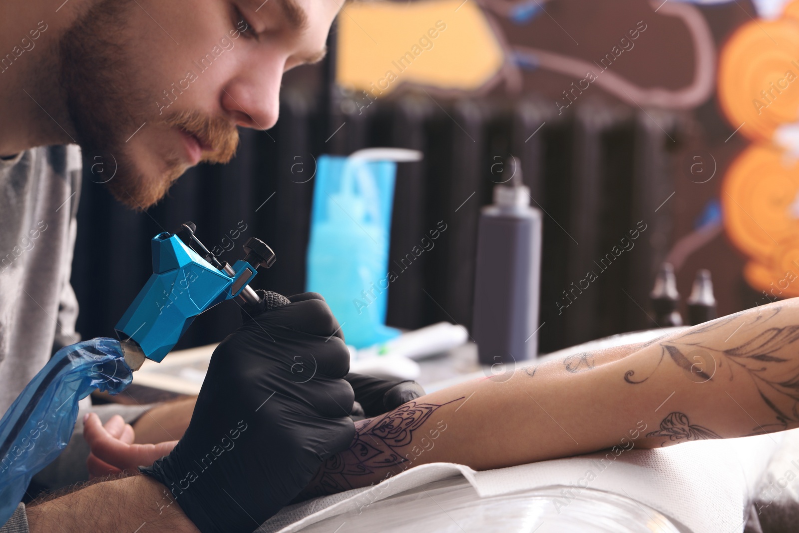 Photo of Professional artist making tattoo on hand in salon, closeup