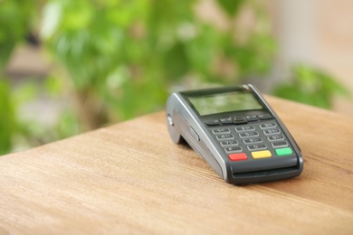 Modern payment terminal on table indoors. Space for text