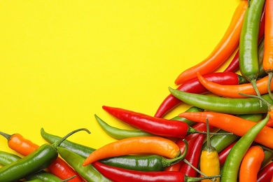 Different hot chili peppers on yellow background, flat lay. Space for text