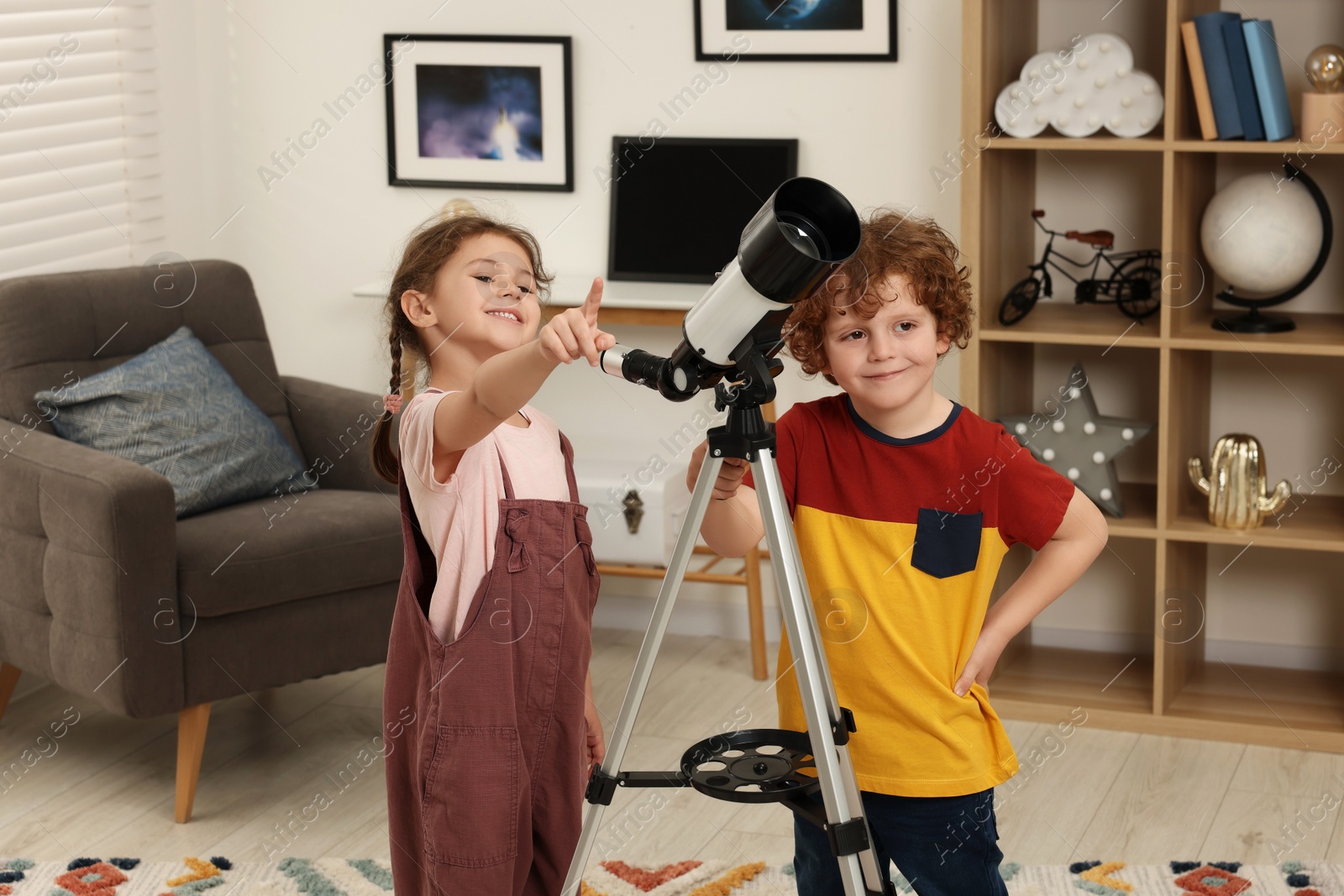 Photo of Cute little children using telescope to look at stars in room