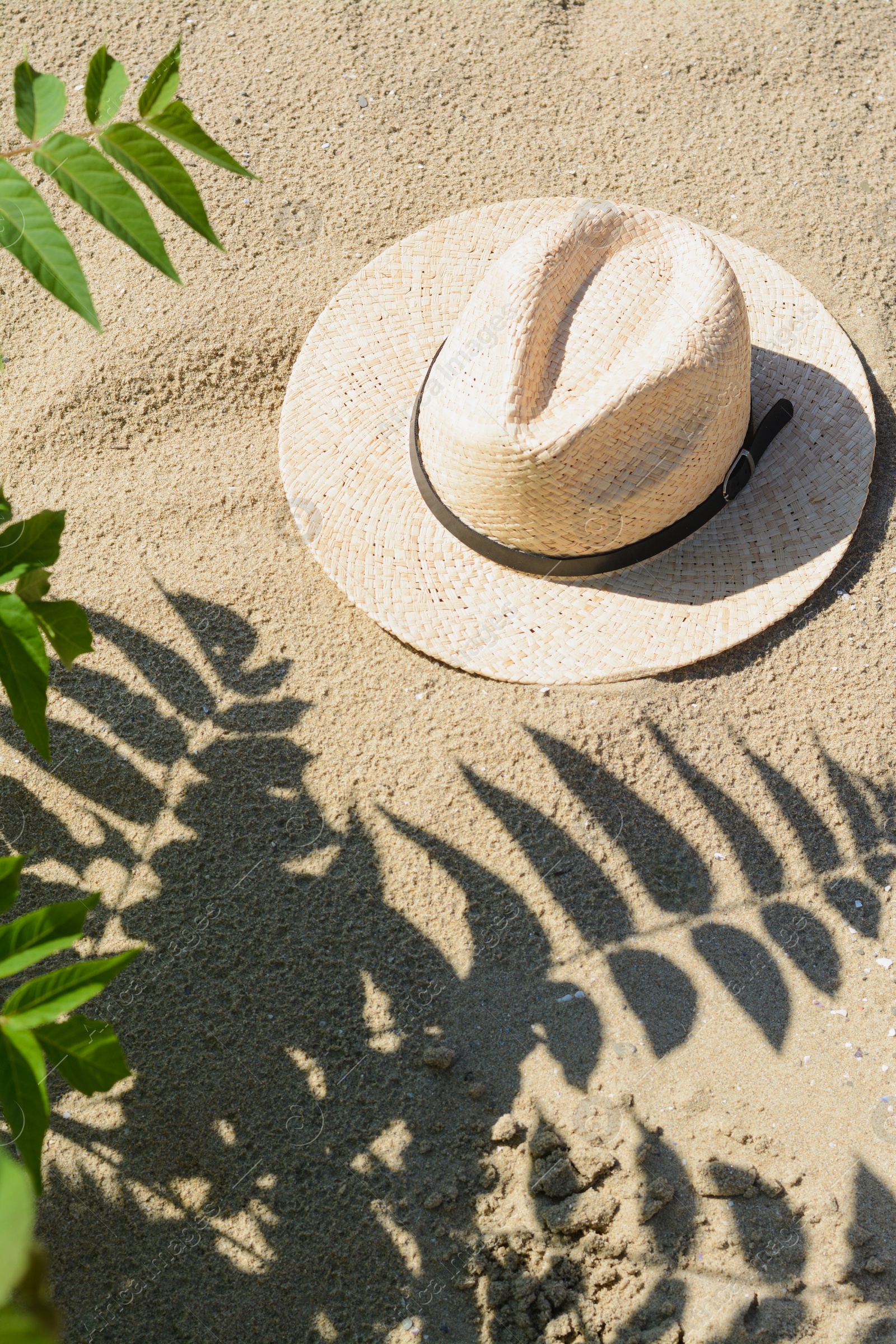 Photo of Stylish straw hat on sand outdoors, above view