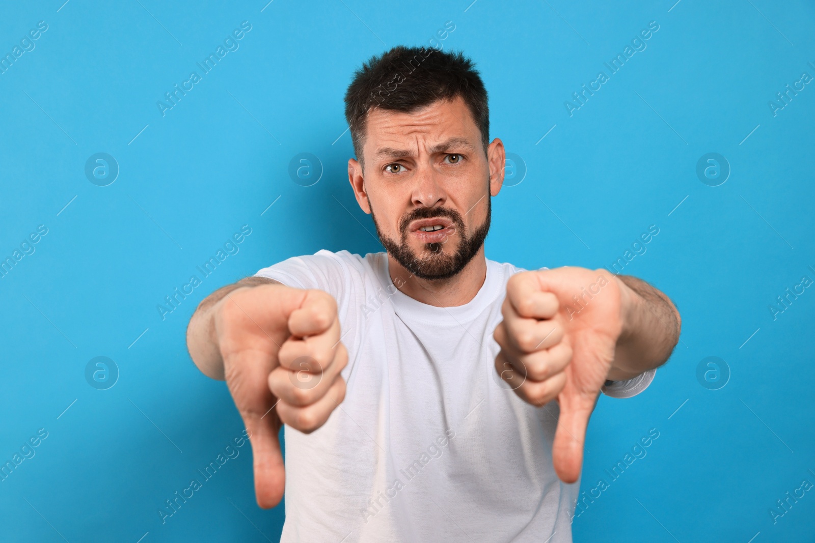 Photo of Man showing thumbs down on light blue background