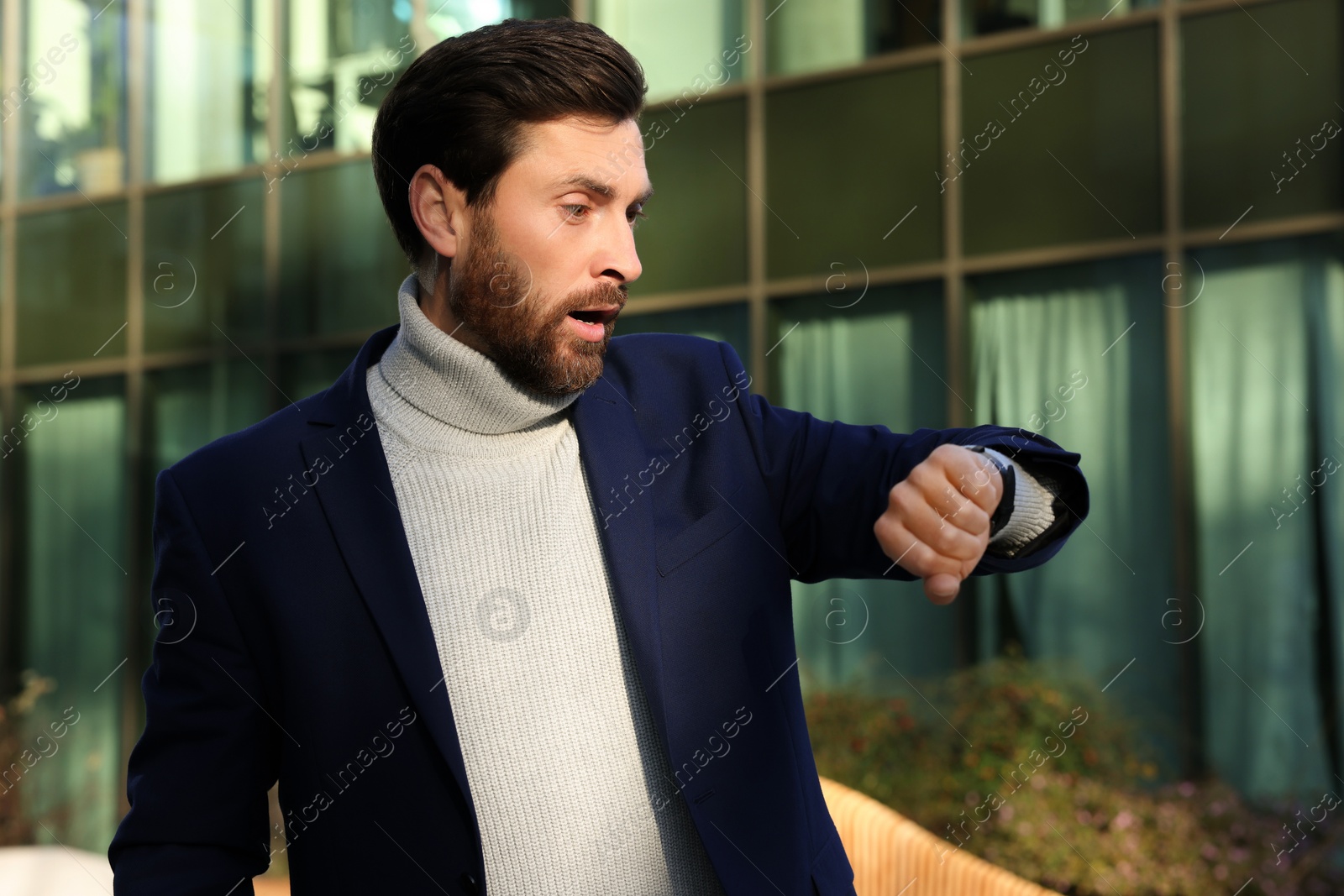 Photo of Businessman checking time on watch near building. Being late concept