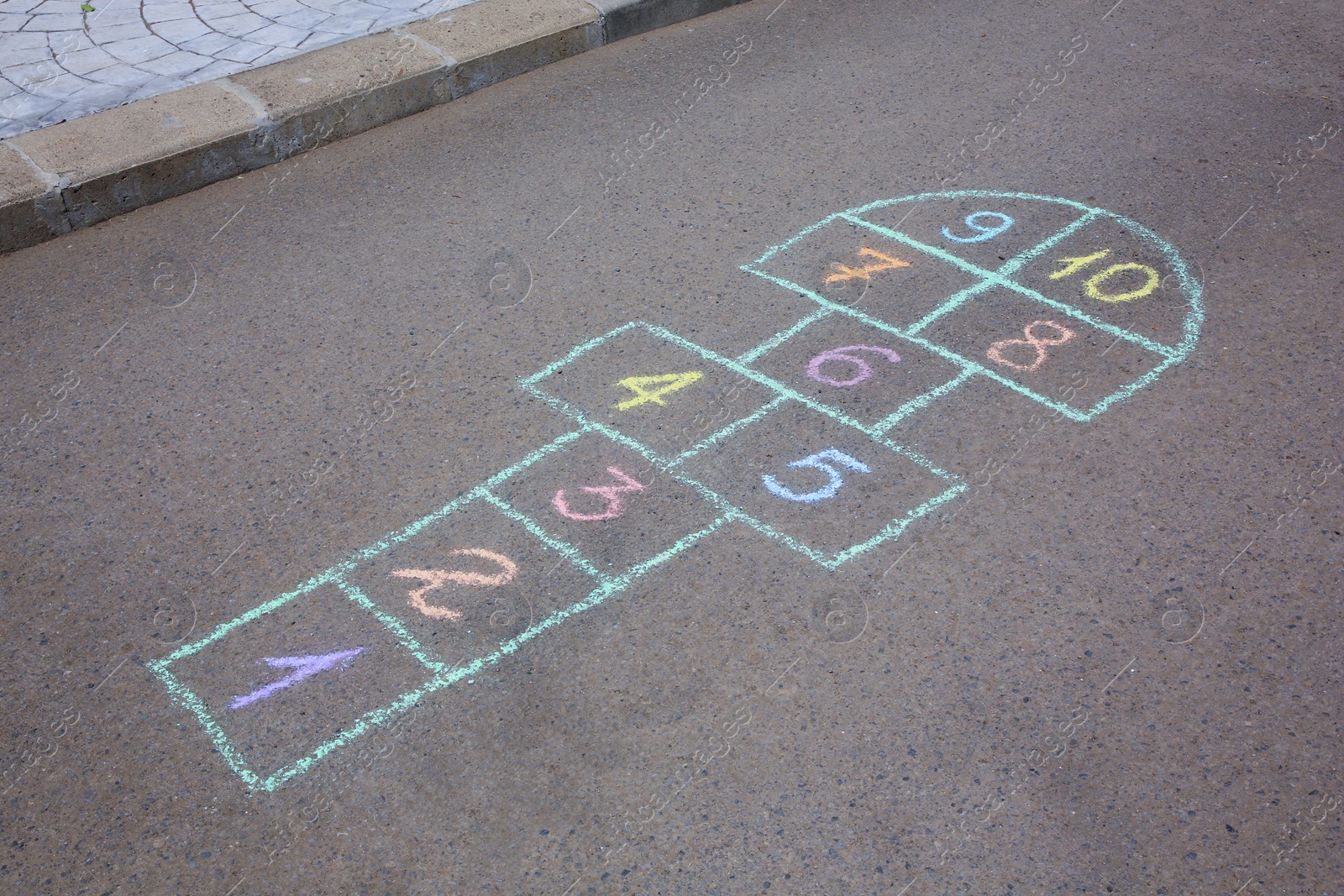 Photo of Hopscotch drawn with colorful chalk on asphalt outdoors