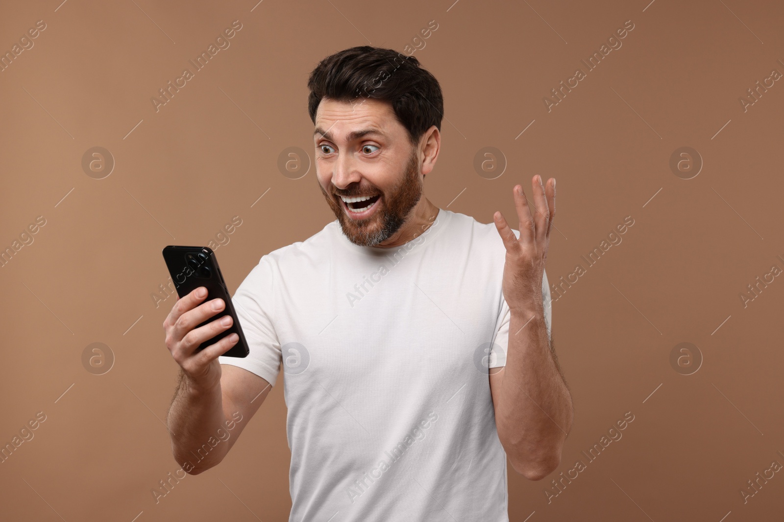 Photo of Happy man with smartphone on light brown background