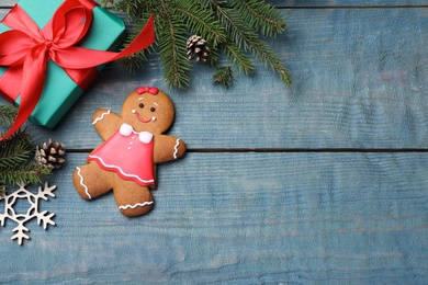 Photo of Flat lay composition with gingerbread girl on blue wooden table, space for text