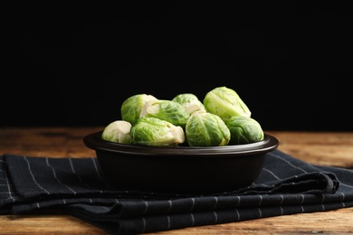 Bowl with fresh Brussels sprouts on wooden table, closeup