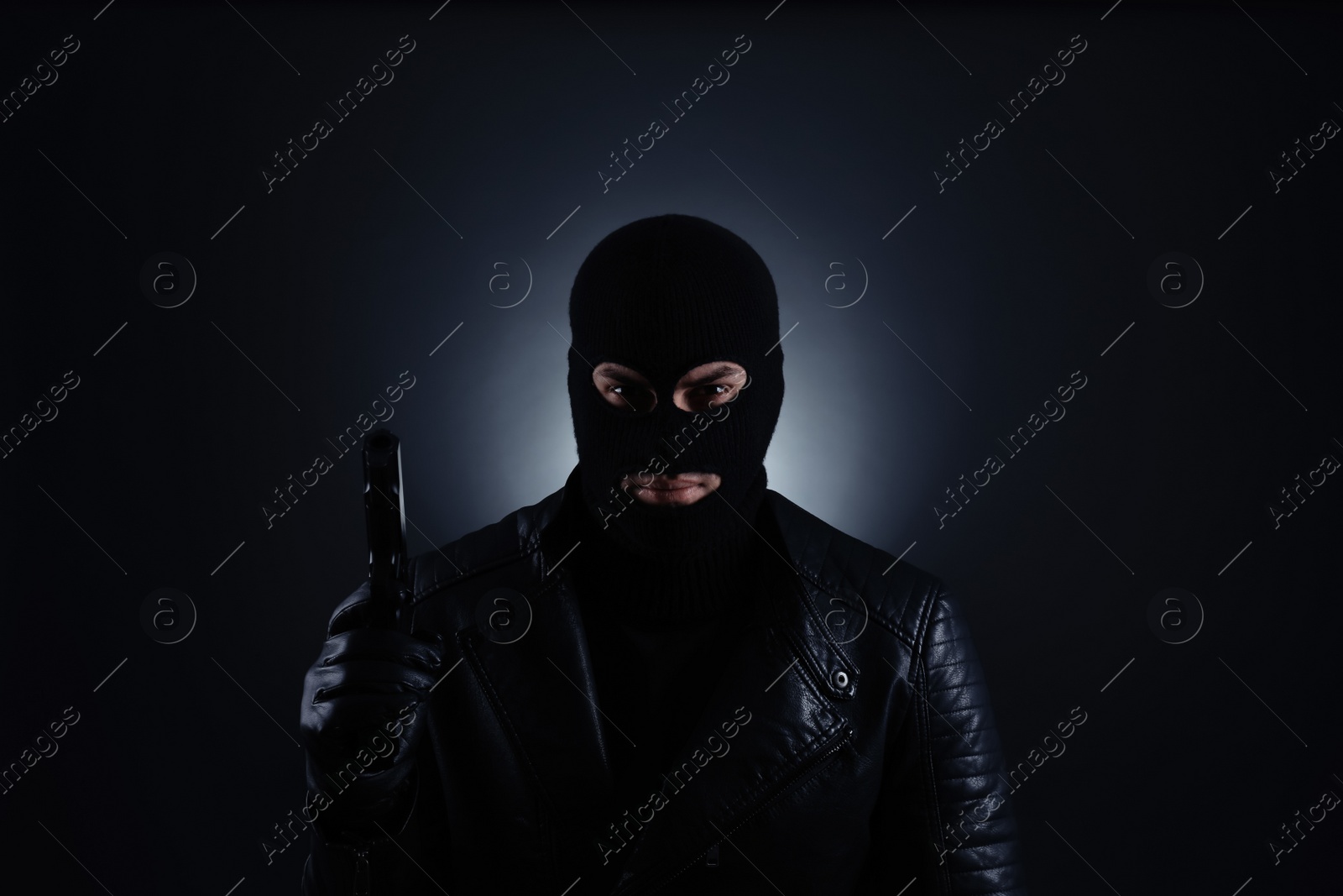 Photo of Man wearing knitted balaclava with gun on black background