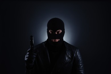 Photo of Man wearing knitted balaclava with gun on black background