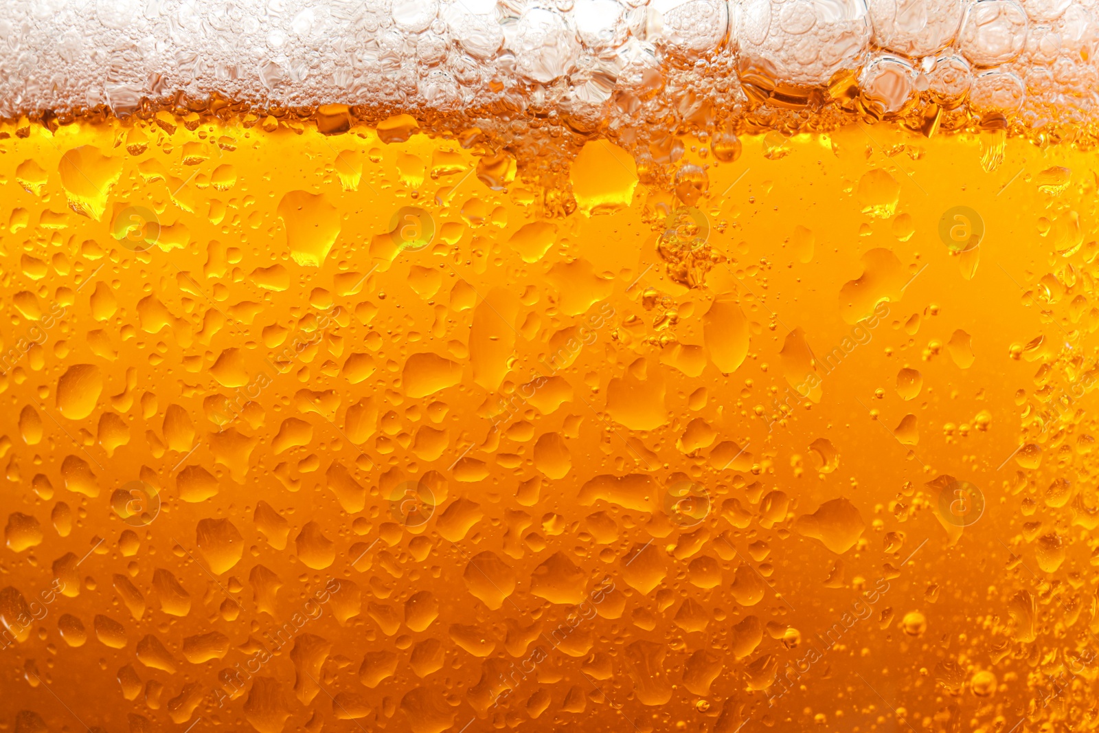 Photo of Glass of tasty cold beer with foam and condensation drops as background, closeup
