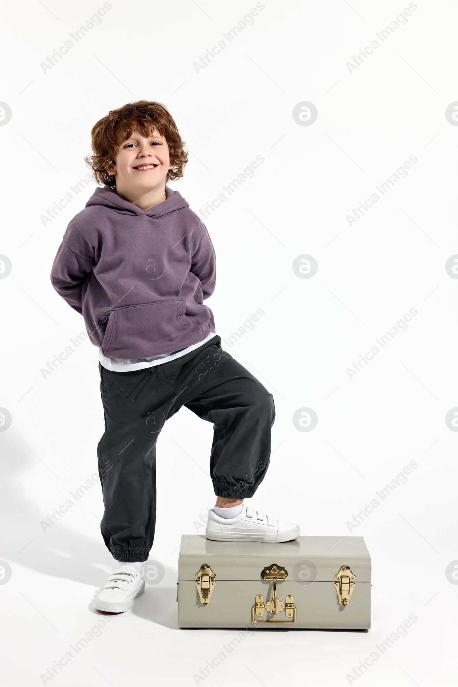 Photo of Fashion concept. Stylish boy with vintage suitcase on white background