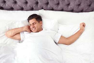 Photo of Man awakening in bed at home, top view. Lazy morning