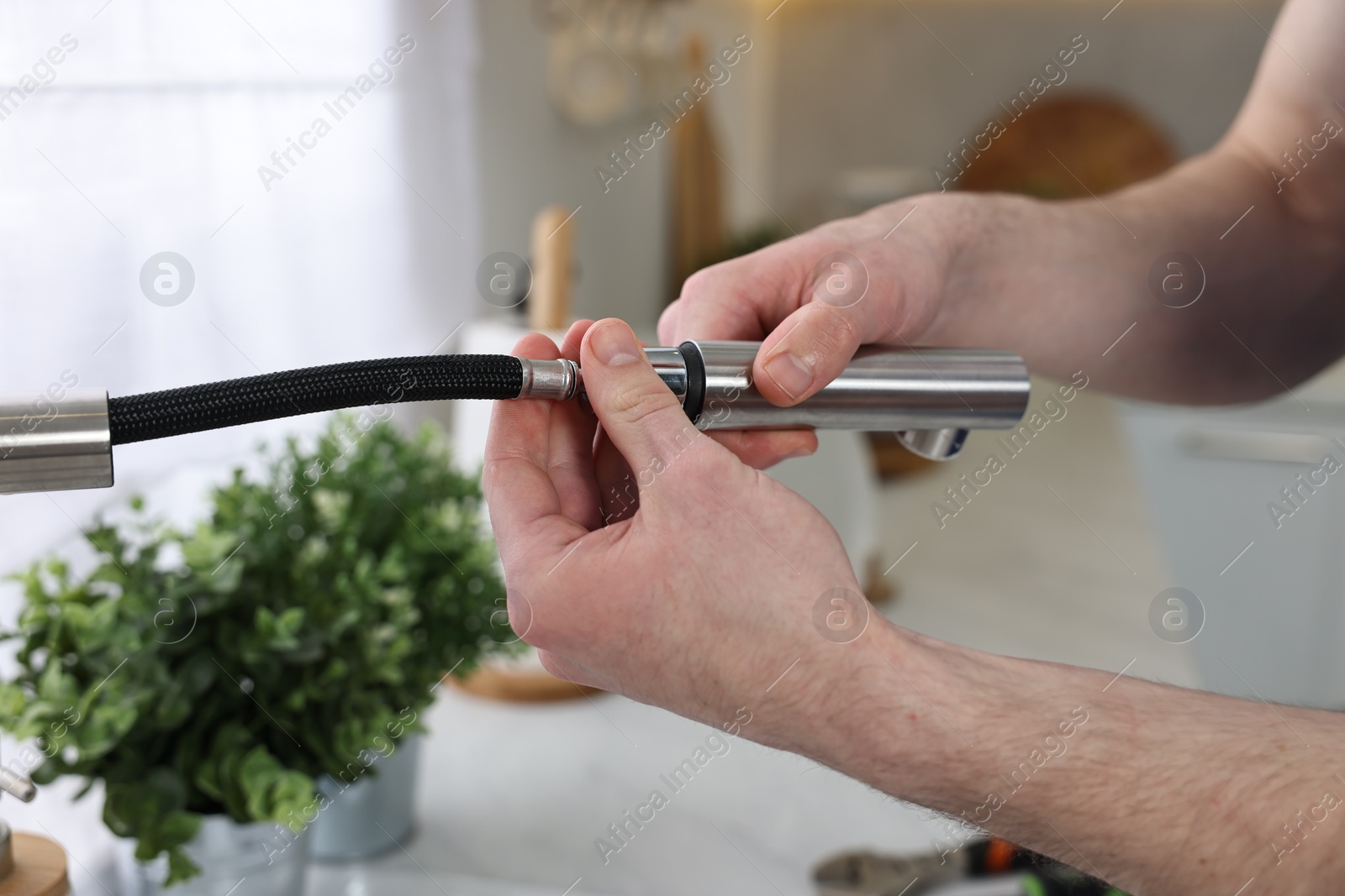 Photo of Plumber examining metal faucet at home, closeup