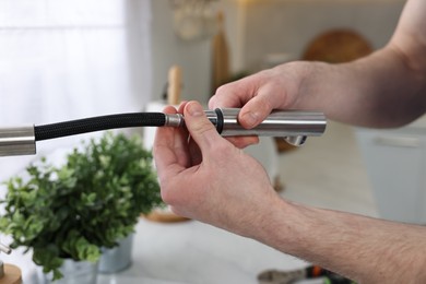 Plumber examining metal faucet at home, closeup