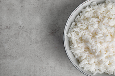 Photo of Bowl with tasty cooked rice on light grey table, top view. Space for text