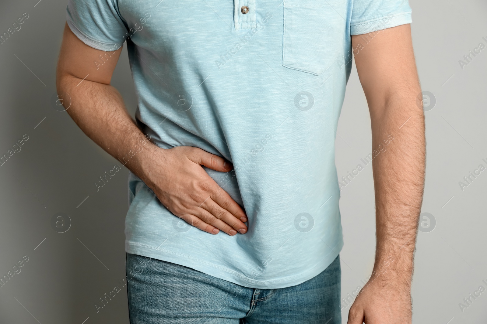 Photo of Man suffering from acute appendicitis on light grey background, closeup