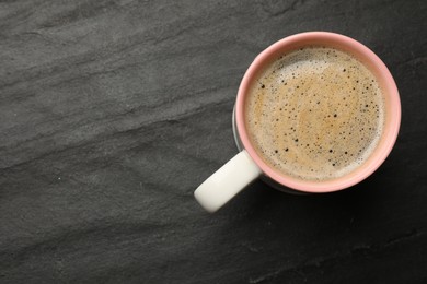 Cup of aromatic coffee on black table, top view. Space for text