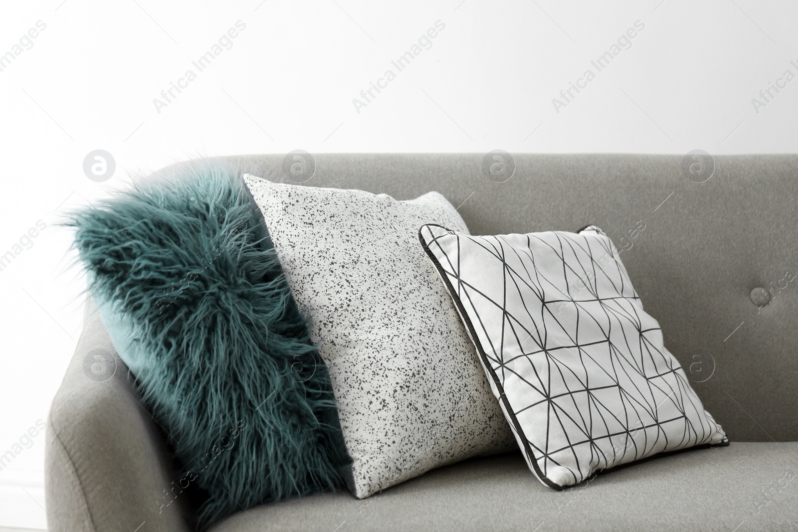 Photo of Sofa with different soft pillows on light background. Interior element