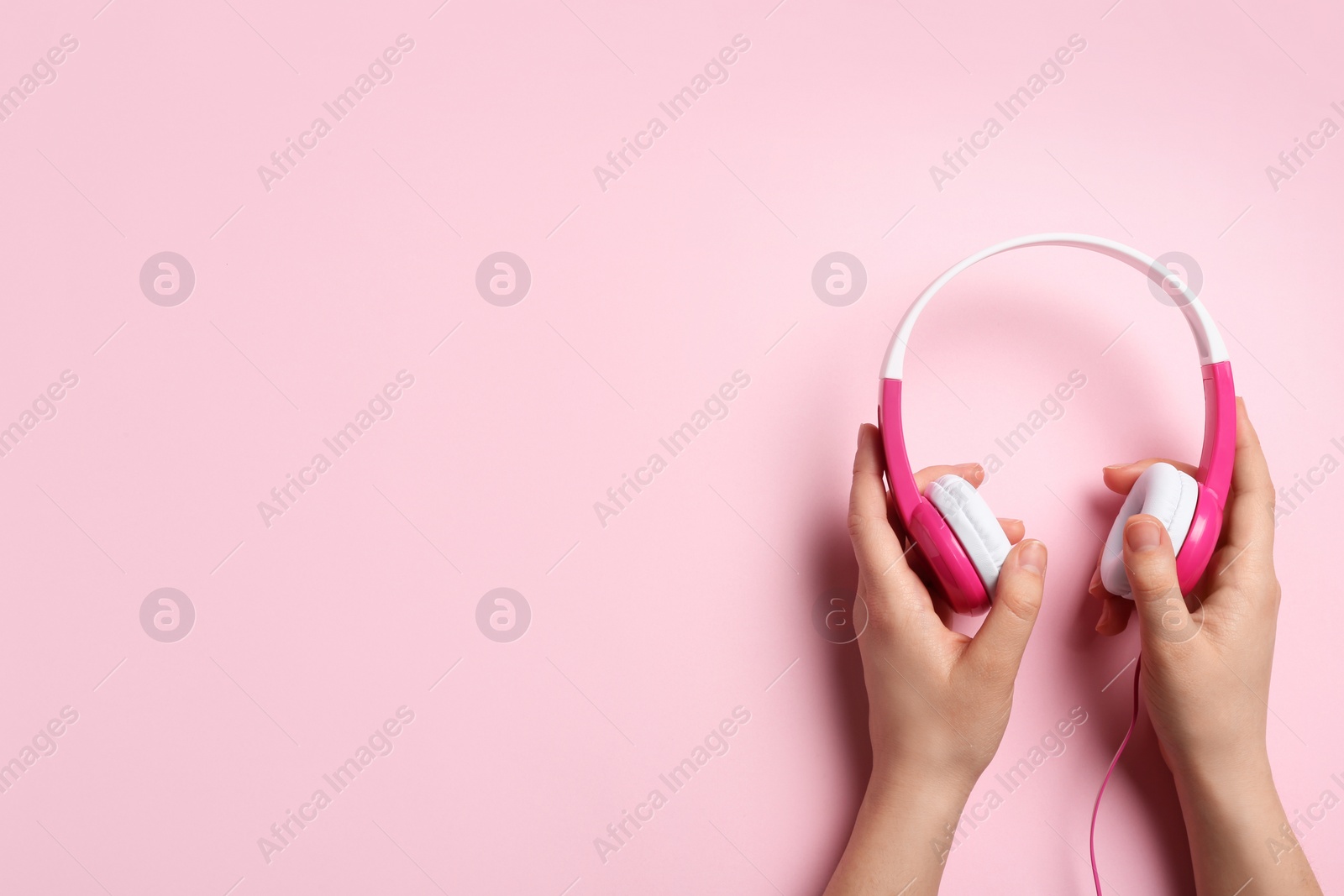 Photo of Woman holding stylish headphones on color background, closeup. Space for text