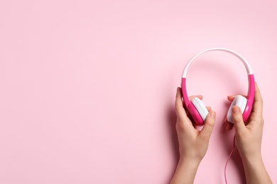 Photo of Woman holding stylish headphones on color background, closeup. Space for text