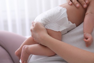 Photo of Mom holding her baby in diaper at home, closeup