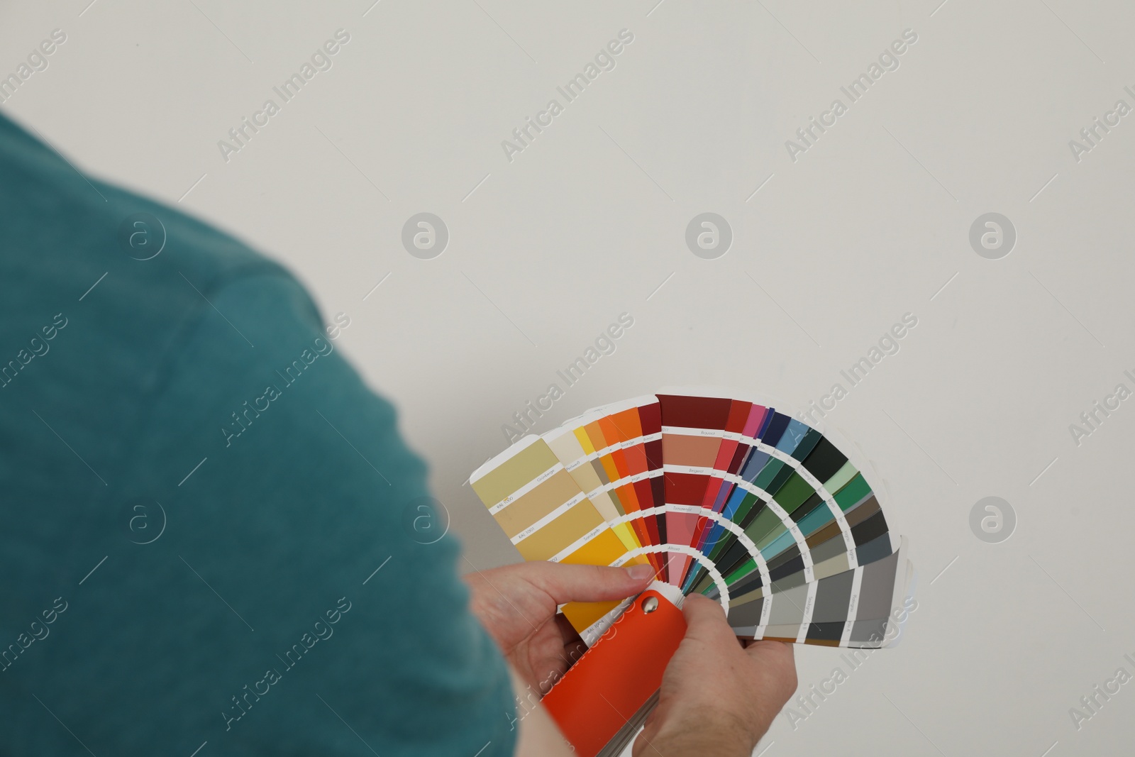 Photo of Man with palette choosing color for painting wall indoors, closeup. Interior design