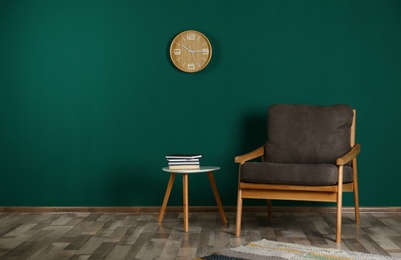 Photo of Stylish room interior with armchair and side table near color wall, space for text