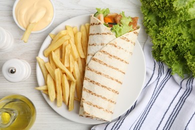 Delicious chicken shawarma and French fries served on white wooden table, flat lay