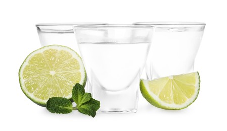 Shot glasses of vodka with lime and mint on white background