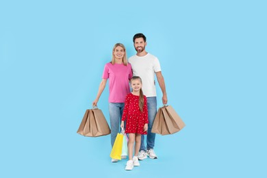 Photo of Happy family with shopping bags on light blue background