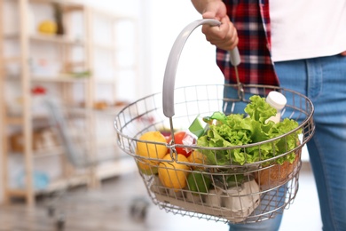 Photo of Man with shopping basket full of products in grocery store, closeup