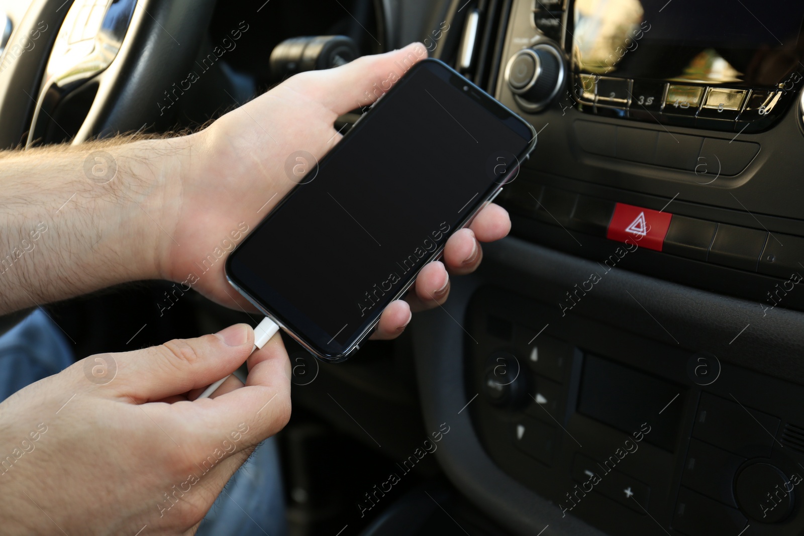 Photo of Man charging phone with USB cable in car