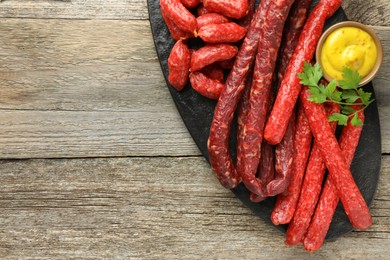 Photo of Thin dry smoked sausages served on old wooden table, top view. Space for text