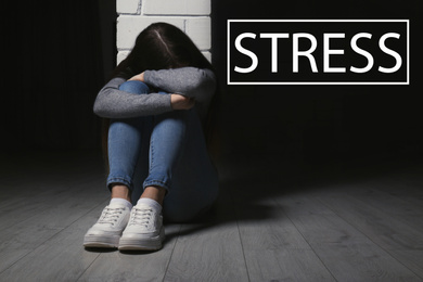 Word STRESS and depressed young girl sitting on floor indoors