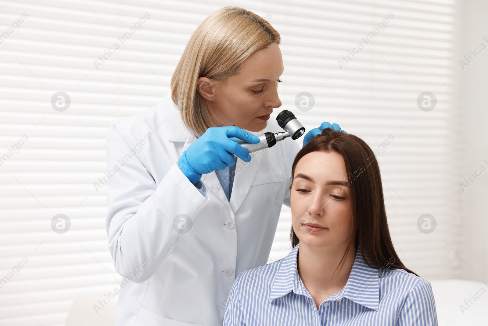 Photo of Trichologist with dermatoscope examining patient`s hair in clinic