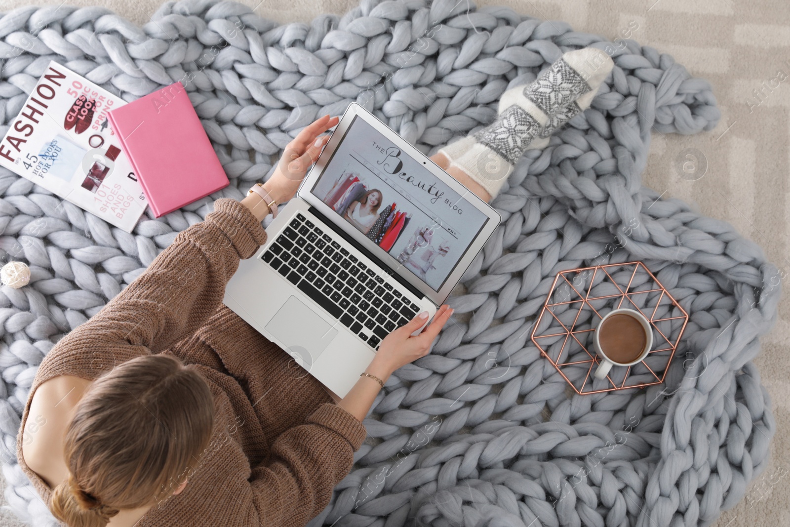 Photo of Woman holding laptop with open beauty blogger site on floor, top view