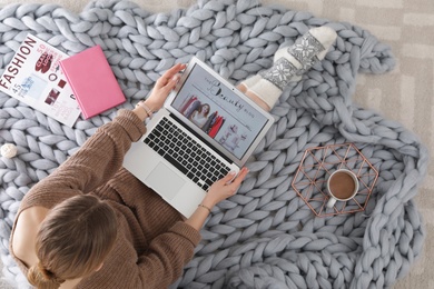 Woman holding laptop with open beauty blogger site on floor, top view