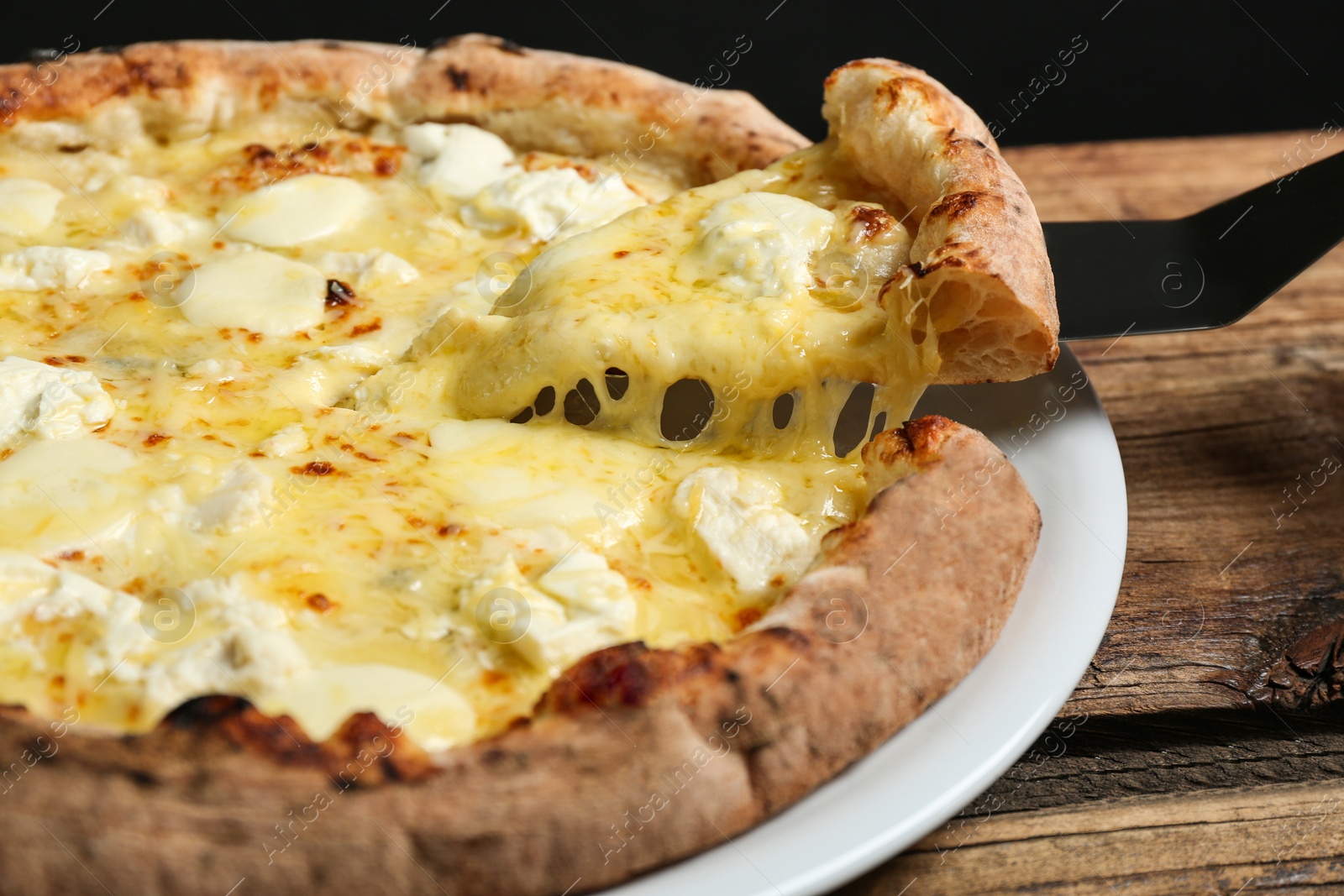 Photo of Taking slice of tasty cheese pizza on wooden table, closeup