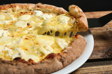 Taking slice of tasty cheese pizza on wooden table, closeup
